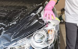Hand using a sponge to wash a car